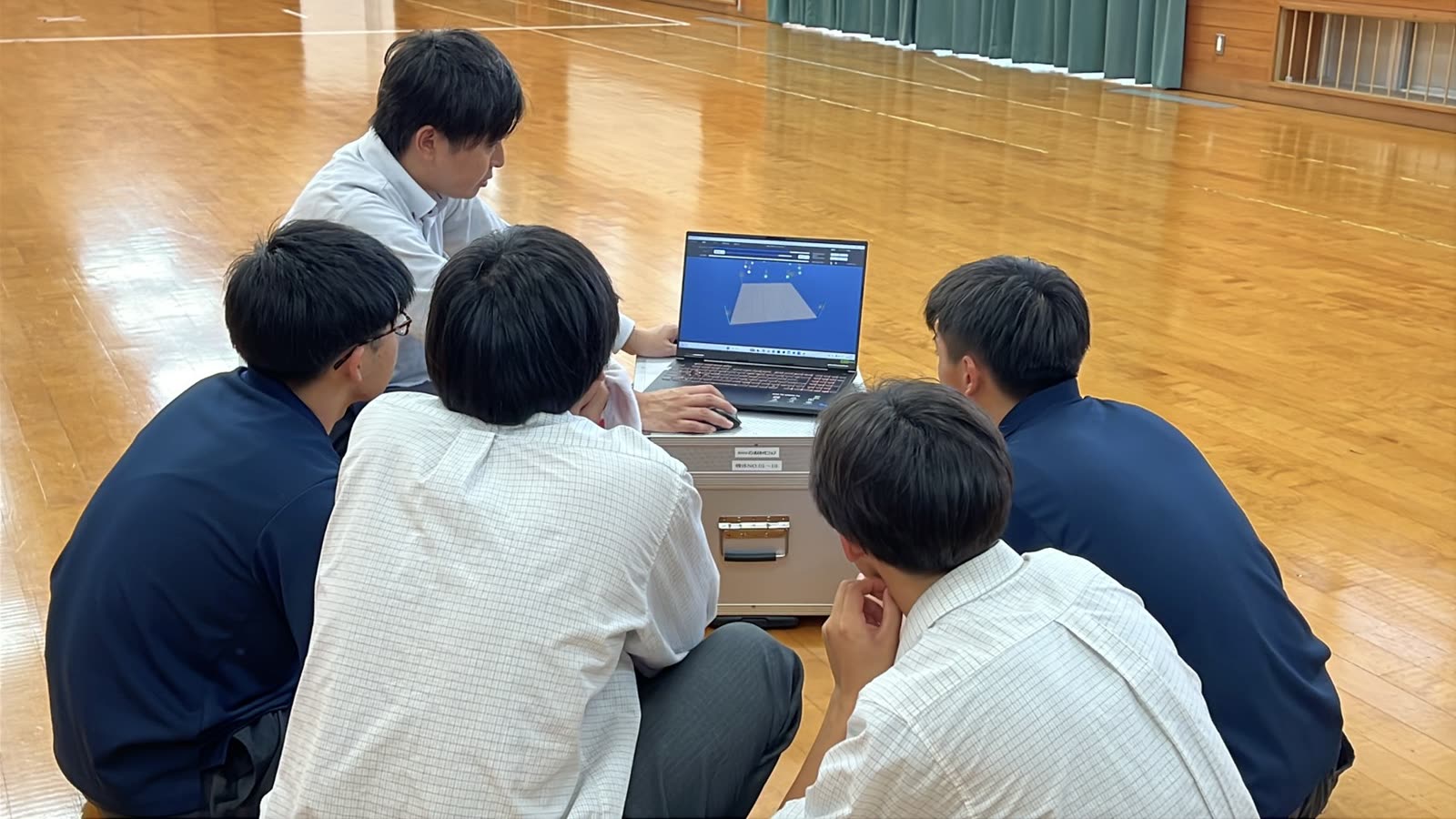 ノートパソコンでドローンショーを設計する高校生